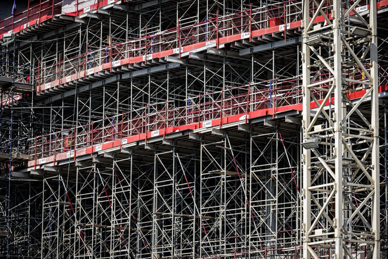 Several storeys of steel scaffolding with red guardrails on a building under construction